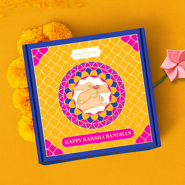 Gift box with 'Happy Raksha Bandhan' text on a yellow background with marigold flowers and plantable rakhi 